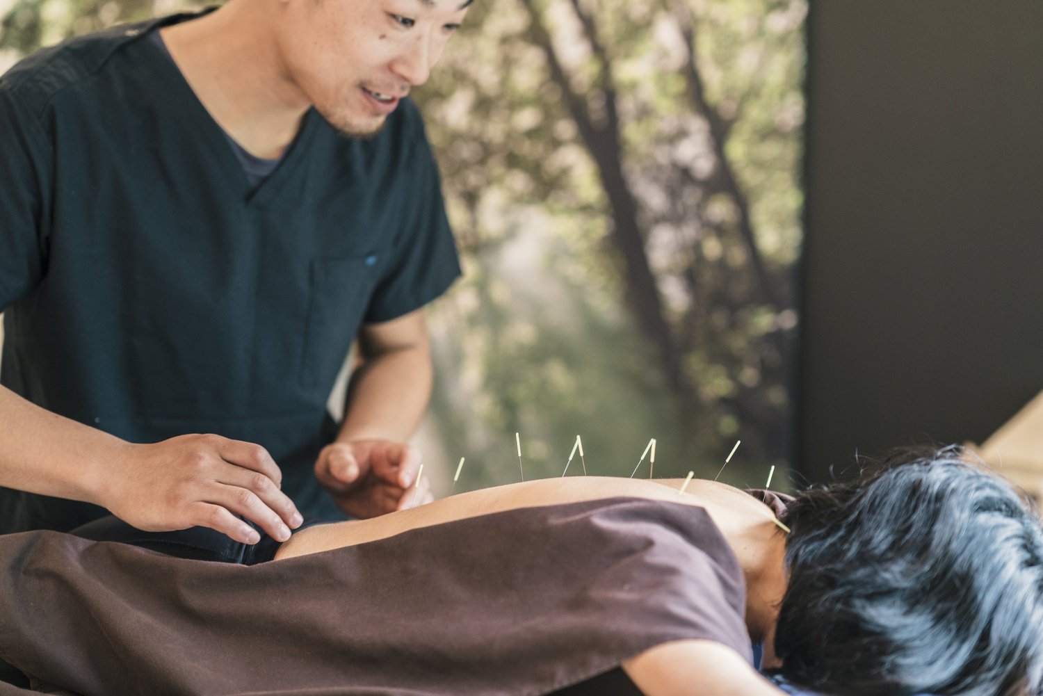 Acupuncturist giving treatment to young patient